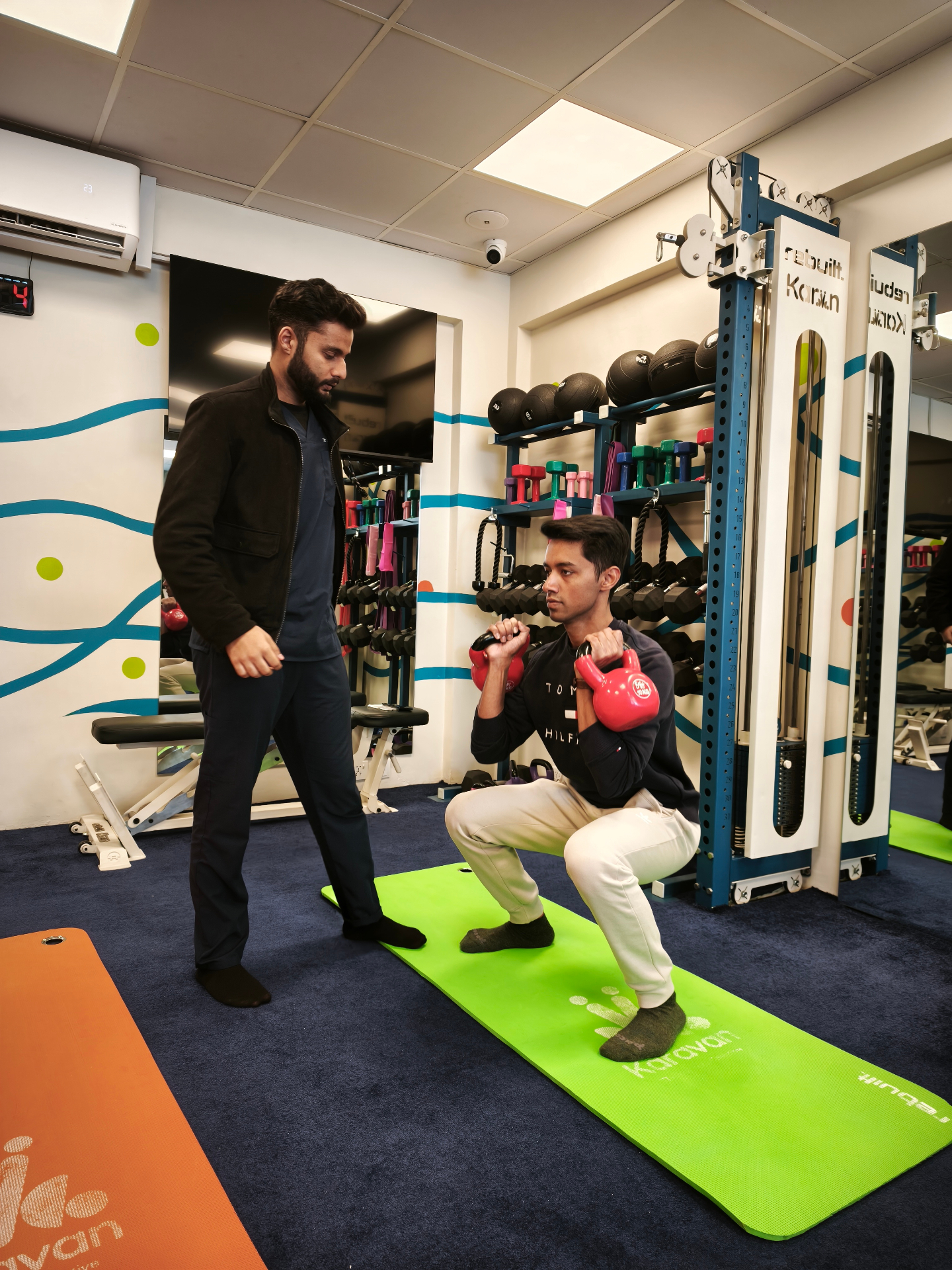 Coach observing a member's kettlebell squat form
