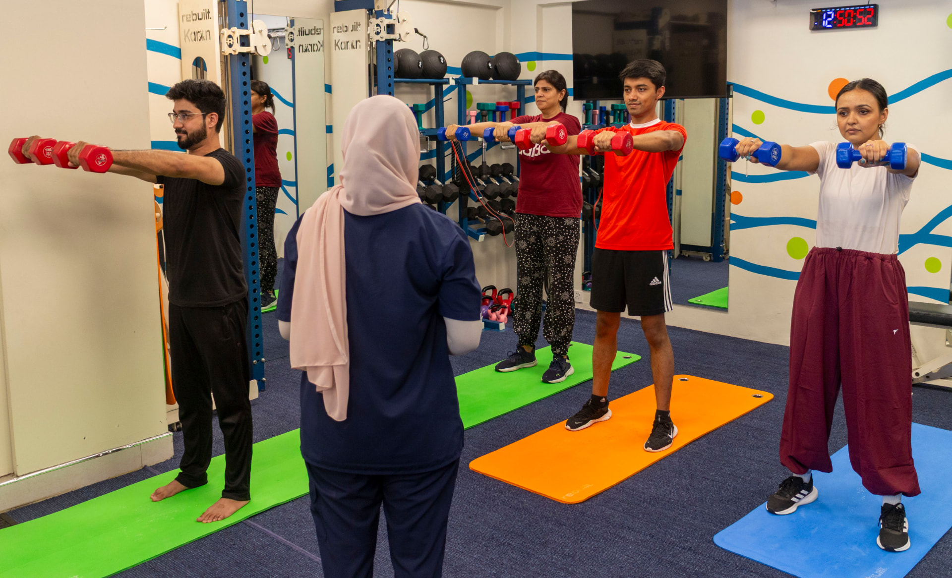 Members performing standing dumbbell raises with their trainer